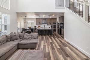 Living room featuring farm house sink, dark LVP flooring, and a towering ceiling