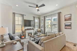 Living room with a stone fireplace, ceiling fan, and hardwood / wood-style floors