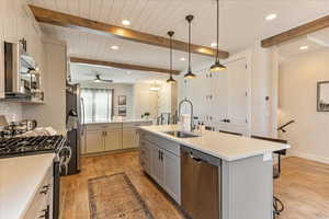 Kitchen featuring ceiling fan, light hardwood / wood-style floors, stainless steel appliances, a center island with sink, and sink