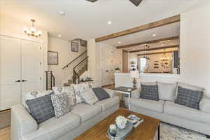 Living room featuring a notable chandelier, beam ceiling, light hardwood / wood-style flooring, and sink