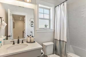 Full bathroom featuring shower / bath combo with shower curtain, toilet, and large vanity