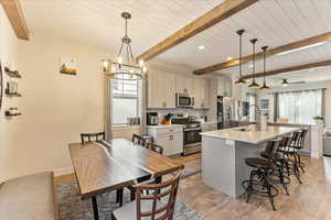 Kitchen with stainless steel appliances, plenty of natural light, light wood-type flooring, and decorative light fixtures