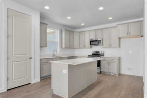 Kitchen featuring sink, gray cabinets, stainless steel appliances, a center island, and light hardwood / wood-style floors