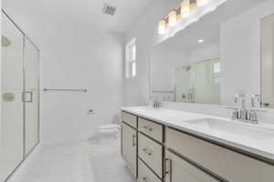 Bathroom featuring an enclosed shower, toilet, and vanity