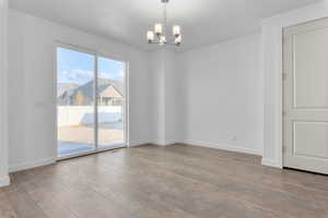 Spare room featuring an inviting chandelier and light hardwood / wood-style floors