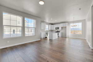 Unfurnished living room featuring light wood-type flooring, a chandelier, and a healthy amount of sunlight