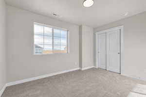 Unfurnished bedroom featuring light colored carpet and a closet