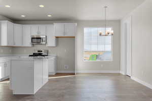 Kitchen with pendant lighting, appliances with stainless steel finishes, a center island, and white cabinetry