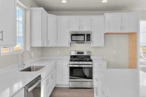 Kitchen featuring white cabinets, light hardwood / wood-style floors, stainless steel appliances, and sink