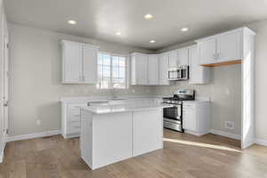 Kitchen featuring a center island, stainless steel appliances, and white cabinets