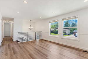 Empty room featuring wood-type flooring and a chandelier