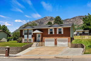 Raised ranch with a mountain view, a garage, and a front lawn