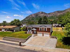 Ranch-style house with a mountain view, a garage, and a front lawn