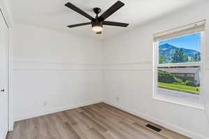 Spare room featuring a mountain view, light wood-type flooring, and ceiling fan