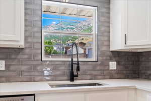 Kitchen featuring sink, decorative backsplash, light stone countertops, and white cabinets