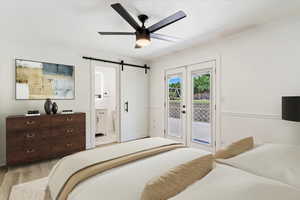 Bedroom featuring connected bathroom, a barn door, access to outside, light wood-type flooring, and ceiling fan. Virtual Staging