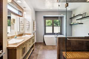 Bathroom featuring vanity, tile patterned flooring, a textured ceiling, and a washtub