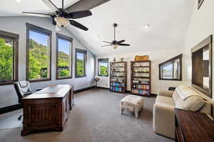 Carpeted home office featuring ceiling fan, vaulted ceiling, and a wealth of natural light