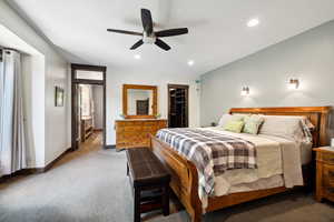 Carpeted bedroom featuring a spacious closet, ceiling fan, and a closet