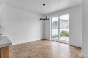 Unfurnished dining area featuring light wood-type flooring, a healthy amount of sunlight, and a chandelier