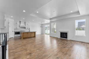 Unfurnished living room with sink, light wood-type flooring, and a tray ceiling