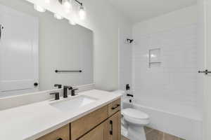 Full bathroom with vanity, toilet, tiled shower / bath combo, and tile patterned floors