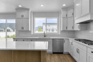 Kitchen with appliances with stainless steel finishes, tasteful backsplash, sink, white cabinetry, and light wood-type flooring