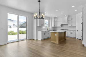 Kitchen featuring light wood-type flooring, white cabinets, and a center island