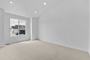 Empty room with light colored carpet and vaulted ceiling