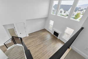 Unfurnished living room with a fireplace, a towering ceiling, and a healthy amount of sunlight