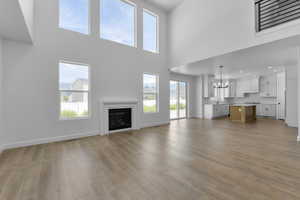 Unfurnished living room with a high ceiling, an inviting chandelier, light hardwood / wood-style floors, and sink