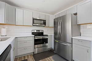 Kitchen with light hardwood / wood-style floors, appliances with stainless steel finishes, and tasteful backsplash