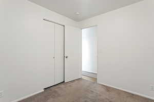 Unfurnished bedroom featuring a closet and light colored carpet