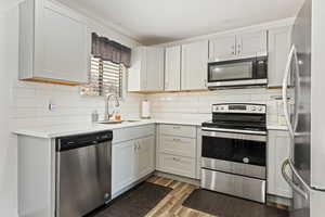 Kitchen with sink, decorative backsplash, light wood-type flooring, and stainless steel appliances