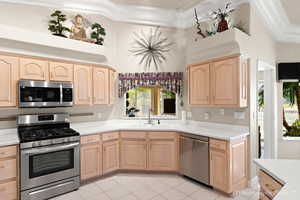 Kitchen with light tile patterned flooring, stainless steel appliances, light brown cabinetry, and sink