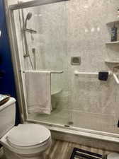 Bathroom featuring toilet, wood-type flooring, and an enclosed shower