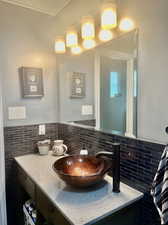 Bathroom featuring vanity and tasteful backsplash