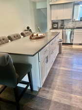 Kitchen featuring stainless steel dishwasher, white cabinetry, hardwood / wood-style flooring, and tasteful backsplash