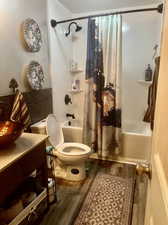 Full bathroom featuring shower / tub combo, wood-type flooring, toilet, and vanity