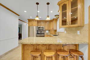 Kitchen featuring kitchen peninsula, backsplash, appliances with stainless steel finishes, sink, and ornamental molding