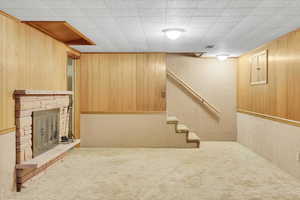 Basement featuring wood walls, carpet floors, and a stone fireplace