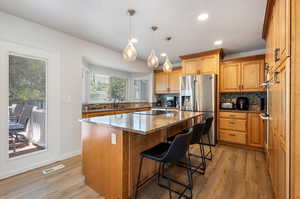 Kitchen featuring a kitchen island, tasteful backsplash, light hardwood / wood-style floors, and stainless steel refrigerator with ice dispenser