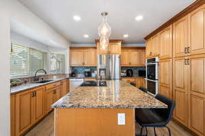 Kitchen with appliances with stainless steel finishes, tasteful backsplash, sink, light hardwood / wood-style floors, and a center island