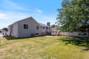 Back of house featuring cooling unit, a yard, and a deck