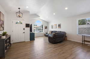 Foyer featuring plenty of natural light, a chandelier, hardwood / wood-style flooring, and vaulted ceiling