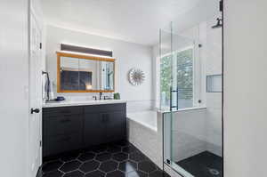 Bathroom featuring plus walk in shower, vanity, and tile patterned floors