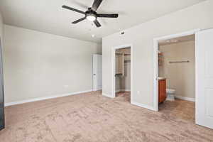 Bedroom with a closet, carpet, connected bathroom, a walk in closet, and ceiling fan