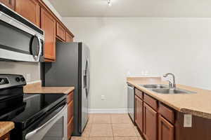 Kitchen featuring light tile patterned flooring, appliances with stainless steel finishes, and sink