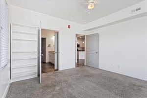 Unfurnished bedroom featuring ensuite bath, ceiling fan, and dark hardwood / wood-style floors