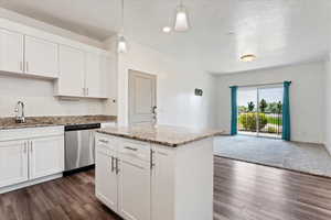 Kitchen with white cabinetry, dark hardwood / wood-style flooring, stainless steel dishwasher, pendant lighting, and sink